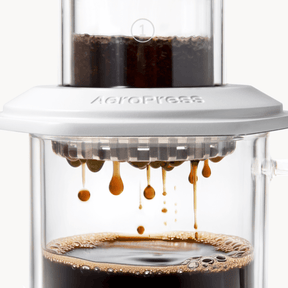 AeroPress Premium coffee maker with coffee being pressed through, showing the brewing process. #color_white