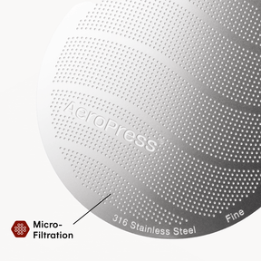 Close-up of a metallic surface with 'Aeropress' branding and text indicating micro-filtration and stainless steel material.