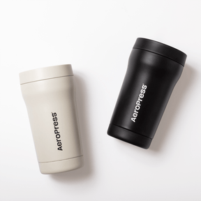 Two AeroPress tumblers, one cream and one black, on a white background #color_cream