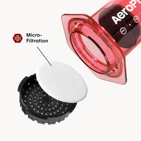 Up close shot of AeroPress Clear Red next to a filter on a white background #color_red