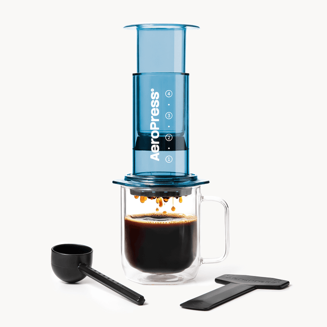 AeroPress coffee maker with a glass mug of brewed coffee on a white background #color_blue