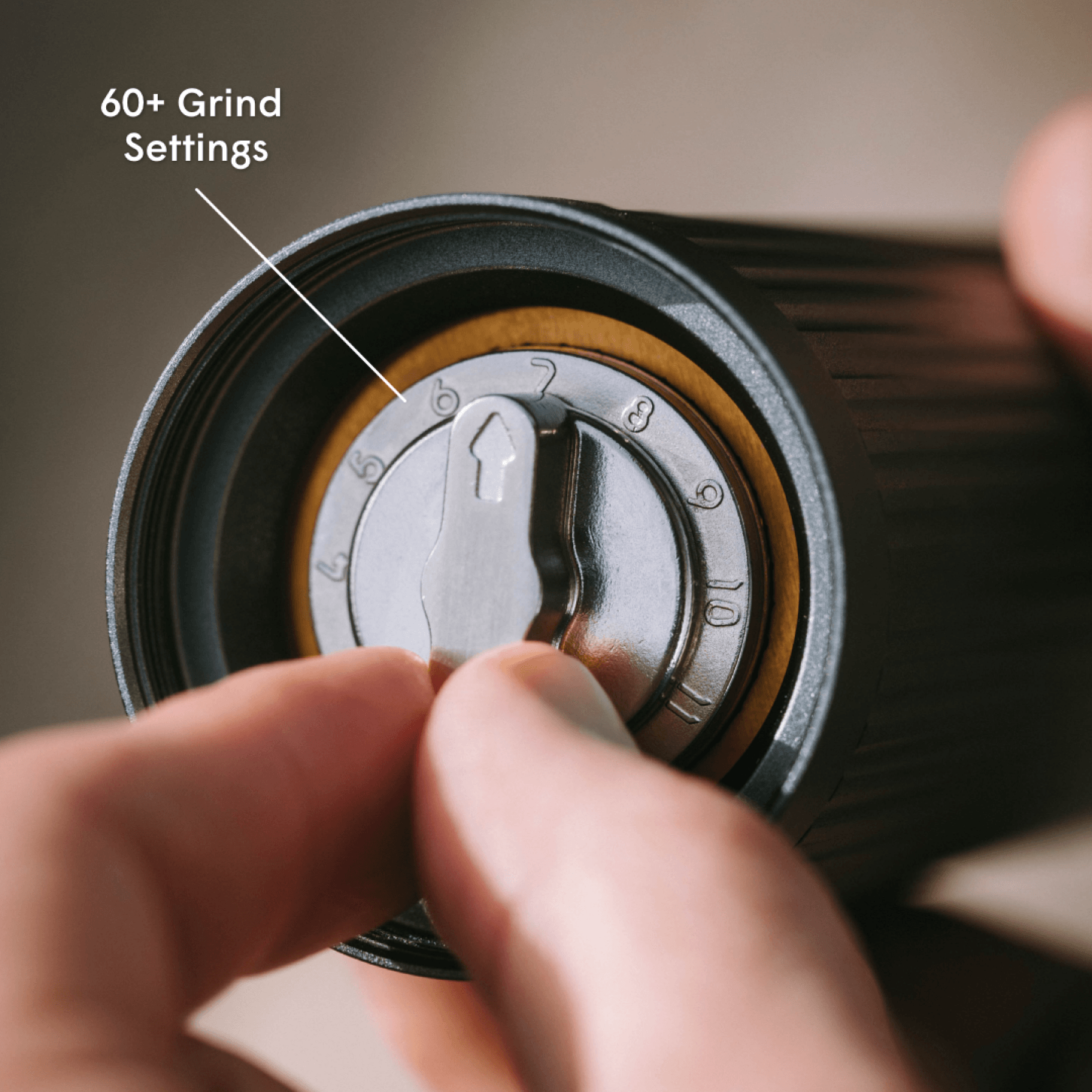 Hand adjusting a coffee grinder with '60+ Grind Settings' text. #color_Clear