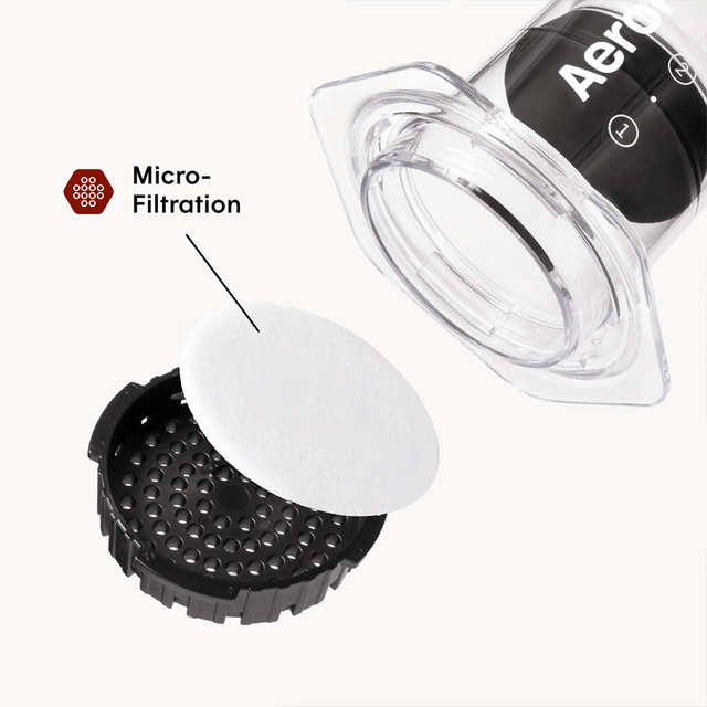 Aeropress coffee maker with a focus on micro-filtration component on a white background #color_clear