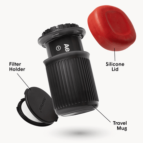 Black travel mug with labeled parts including a red silicone lid and AeroPress Go travel coffee maker on a white background
