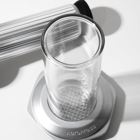 Clear glass AeroPress Premium chamber with metal base on a white  surface #color_silver