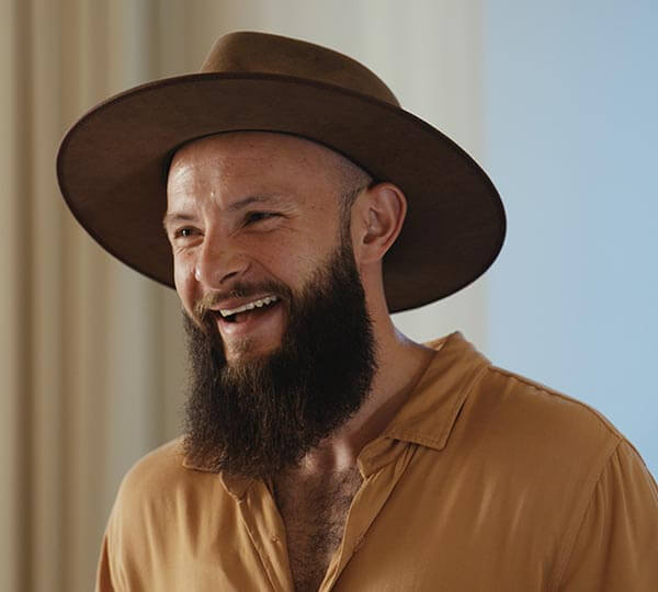 Man wearing a brown hat and beige shirt with a blurred background