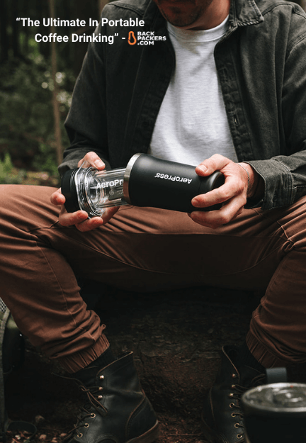 Person brewing coffee outdoors with AeroPress Go Plus travel coffee maker