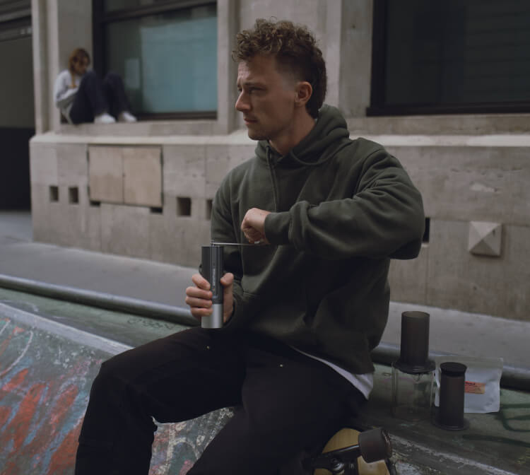 Man sitting on a bench holding a cup in an urban setting